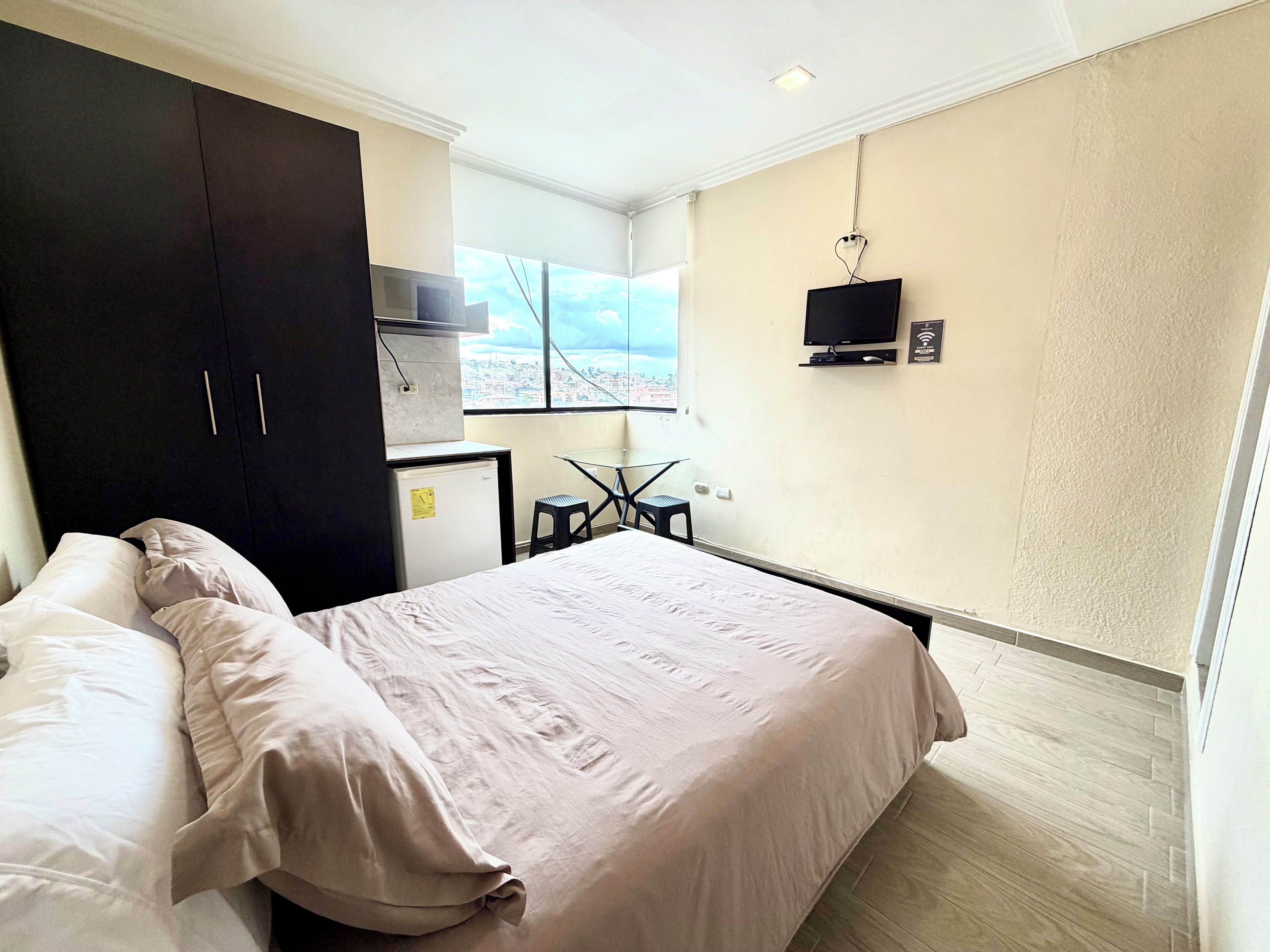 Una camera da letto con un letto, una scrivania, una TV e un armadio.
