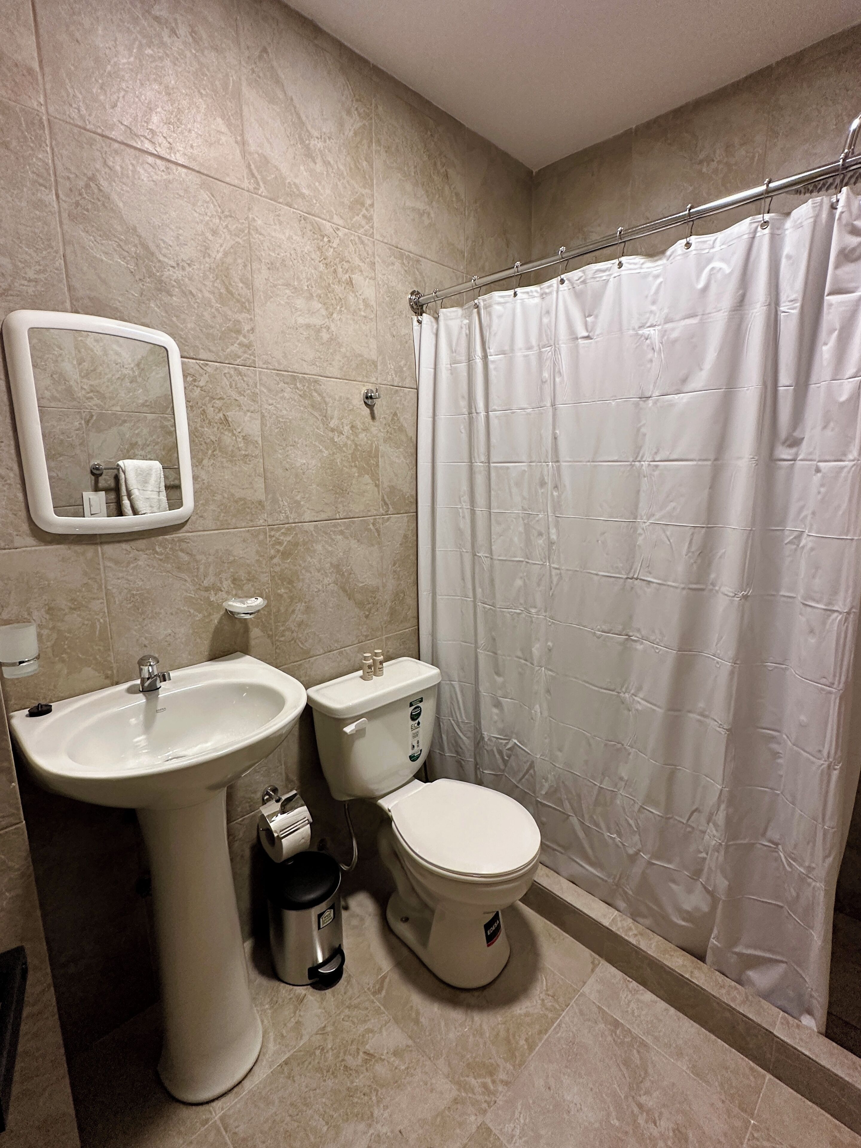 Un baño con lavamanos, inodoro y cortina de ducha.