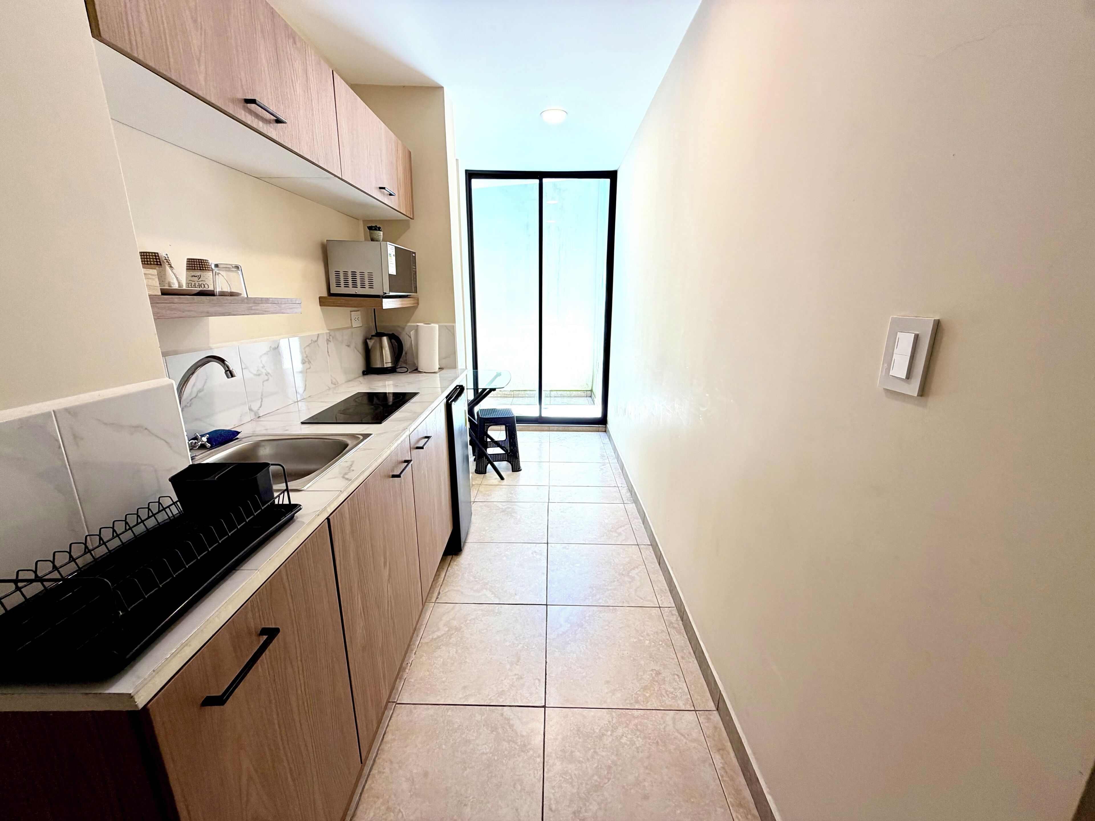 Una cocina con lavamanos, estufa, microondas y armarios. Hay una ventana con vistas al exterior.