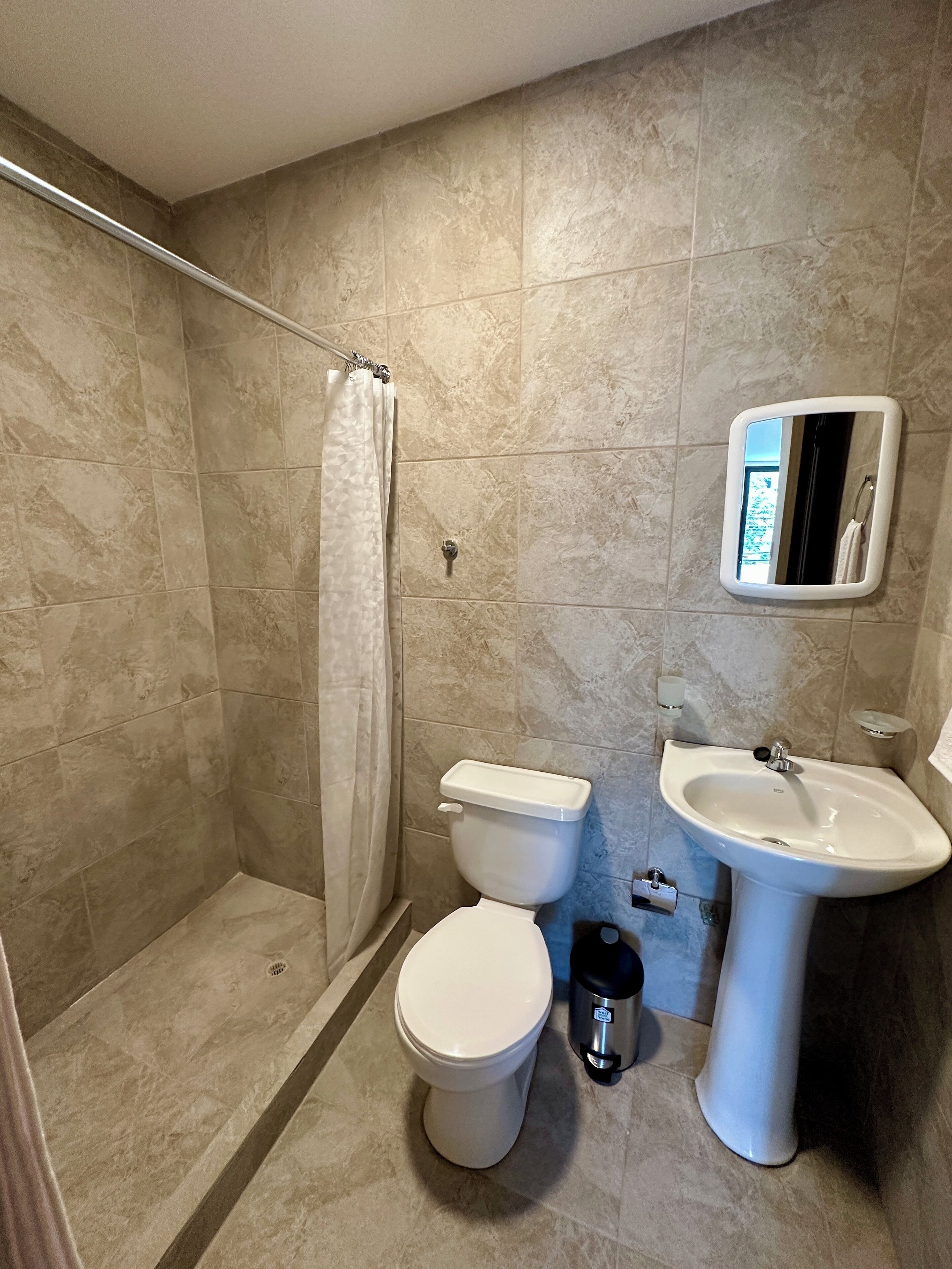 Un baño con ducha, inodoro y lavamanos.
