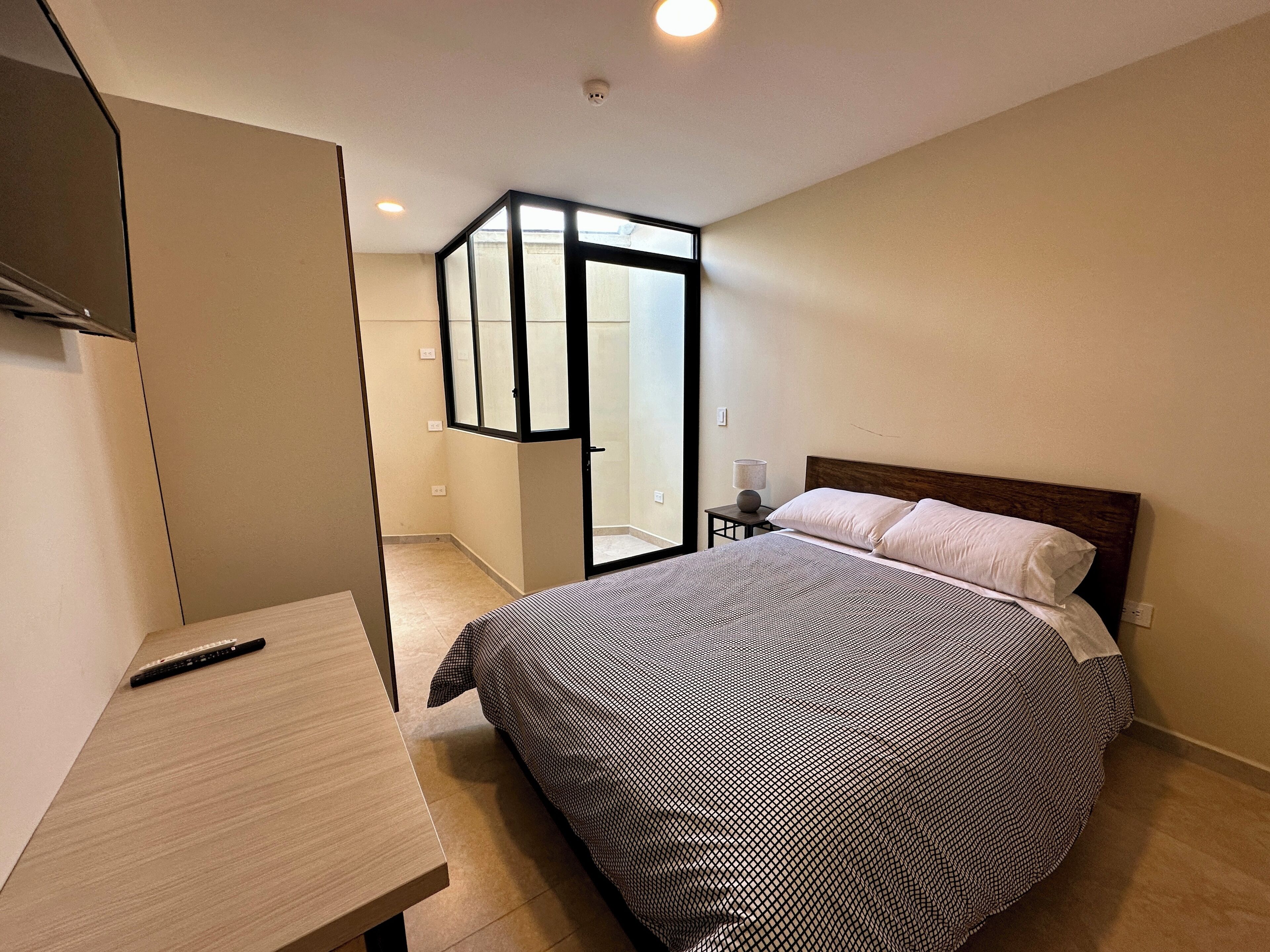 Ein Schlafzimmer mit Bett, Schreibtisch und einer Schiebetür zu einem Badezimmer.