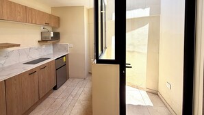 Une cuisine de taille réduite, dotée de meubles en bois, d’un four à micro-ondes et d’un lave-vaisselle.