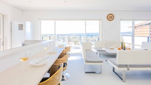 A modern dining area with a long counter, multiple chairs, and a view of the city. - Nanki shirahama View point (Shirahama)