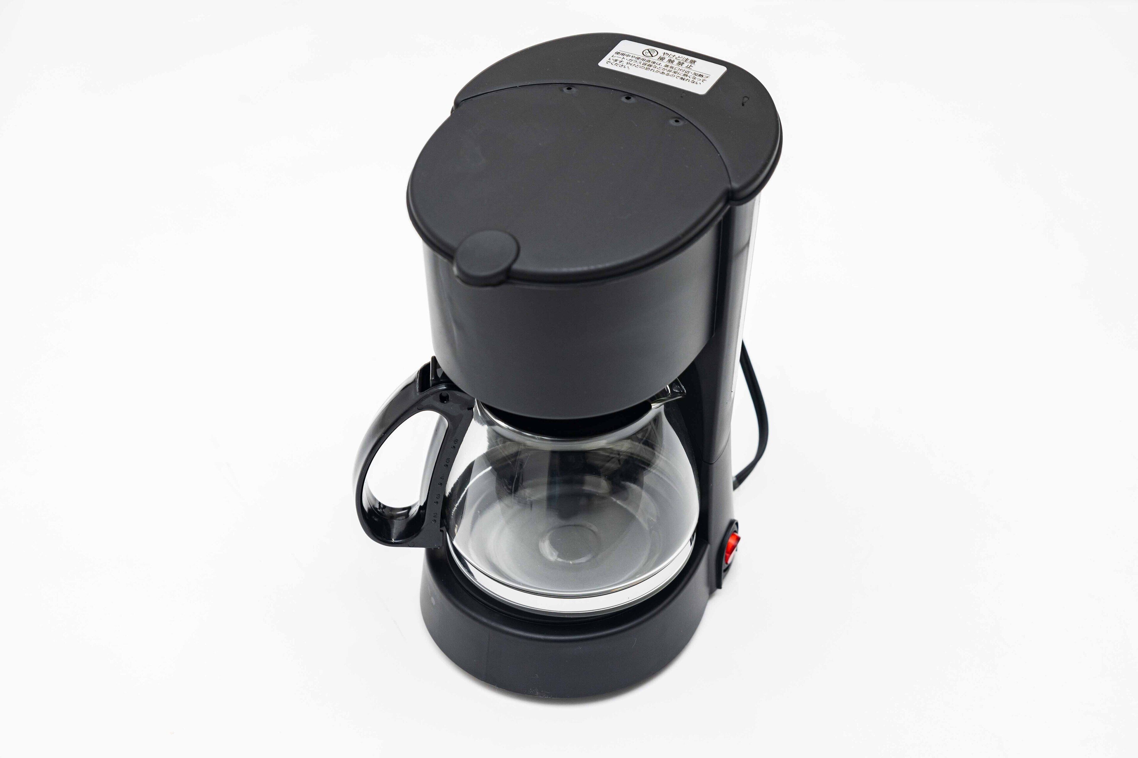 Una cafetera negra con depósito de agua transparente y tapa.