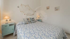 Ein Schlafzimmer mit einem Bett, zwei Nachttischen und Wanddekorationen.