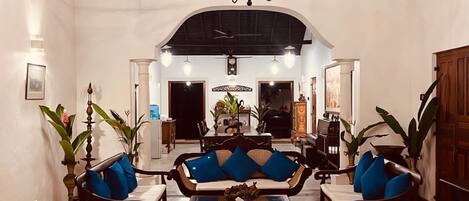 A spacious room with a high ceiling, a chandelier, and a seating area with a sofa and chairs.