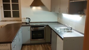 Una cucina compatta con forno integrato, lavello in acciaio inossidabile e bollitore sul piano di lavoro.