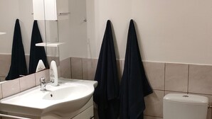 Un bagno con lavandino bianco, specchio e servizi igienici. Due asciugamani sono appesi al muro.