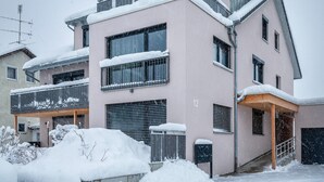 A multi-story building with balconies, a garage, and a covered entrance. - Studio Apartment 'Ferienwohnung Legau' with Wi-Fi (Legau)