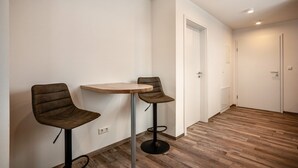 A room with two bar stools, a small round table, and a door leading to another room. - Studio Apartment 'Ferienwohnung Legau' with Wi-Fi (Legau)