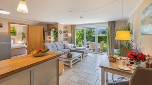 A modern living room with a sofa, a dining table, and a kitchen area.