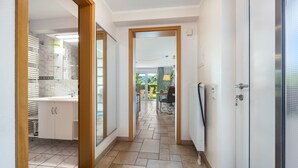 A hallway with a kitchen area, a dining area, and a view of the outdoors.