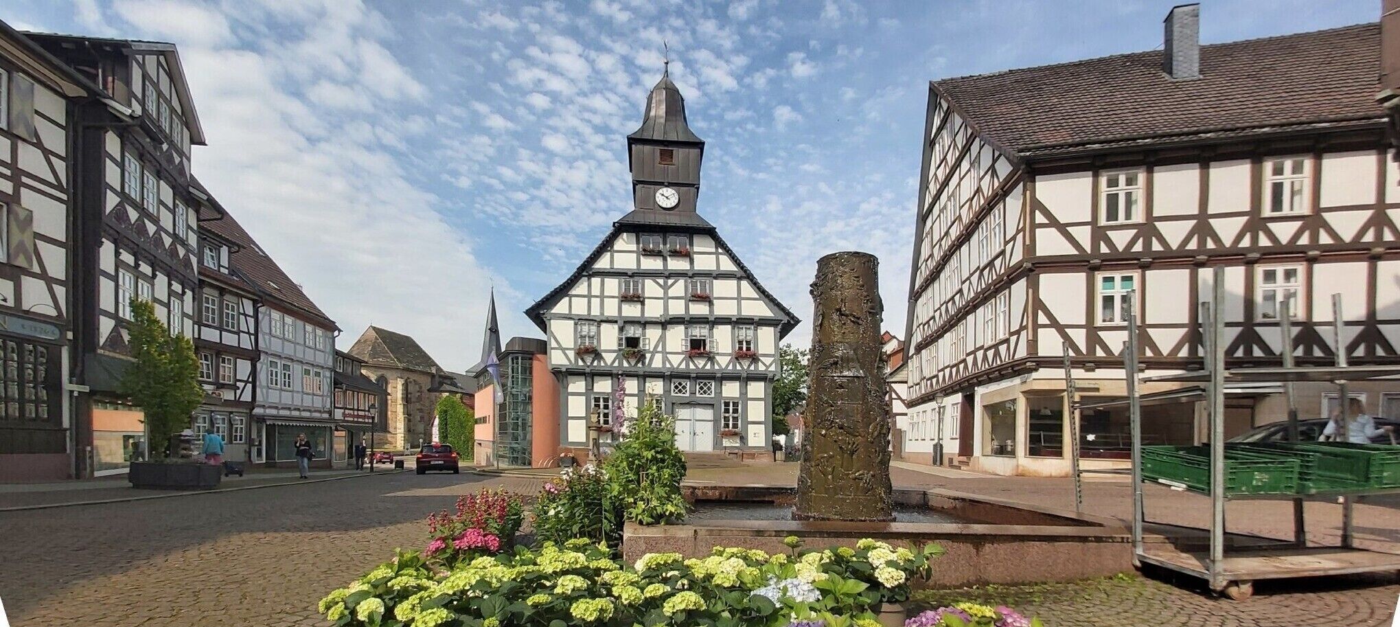 Een typisch Europees stadsplein met vakwerkhuizen, een centraal gelegen klokkentoren en een fontein.