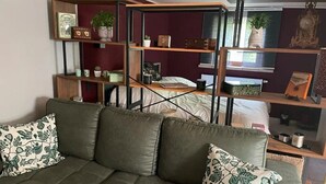 A room with a green sofa, wooden shelves, and various decorative items. - Apartment 'Bella Petit' with Private Terrace and Wi-Fi (Büdingen (Wolferborn))