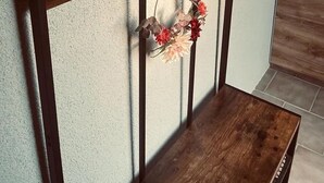 A wall-mounted coat rack with hooks and a shelf, a wooden bench, and a floral wreath. - Apartment 'Bella Petit' with Private Terrace and Wi-Fi (Büdingen (Wolferborn))