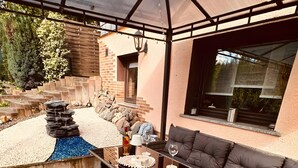 A covered patio area with a seating arrangement, a small water feature, and a view of the surrounding landscape. - Apartment 'Bella Petit' with Private Terrace and Wi-Fi (Büdingen (Wolferborn))