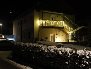 Un edificio a due piani con un balcone, una scala e terreno innevato.