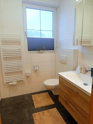 Un bagno moderno con il water, un lavandino e una finestra con persiane.