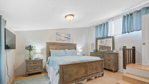 Un dormitorio con una cama de madera, mesitas de noche, un aparador, un espejo y una escalera.