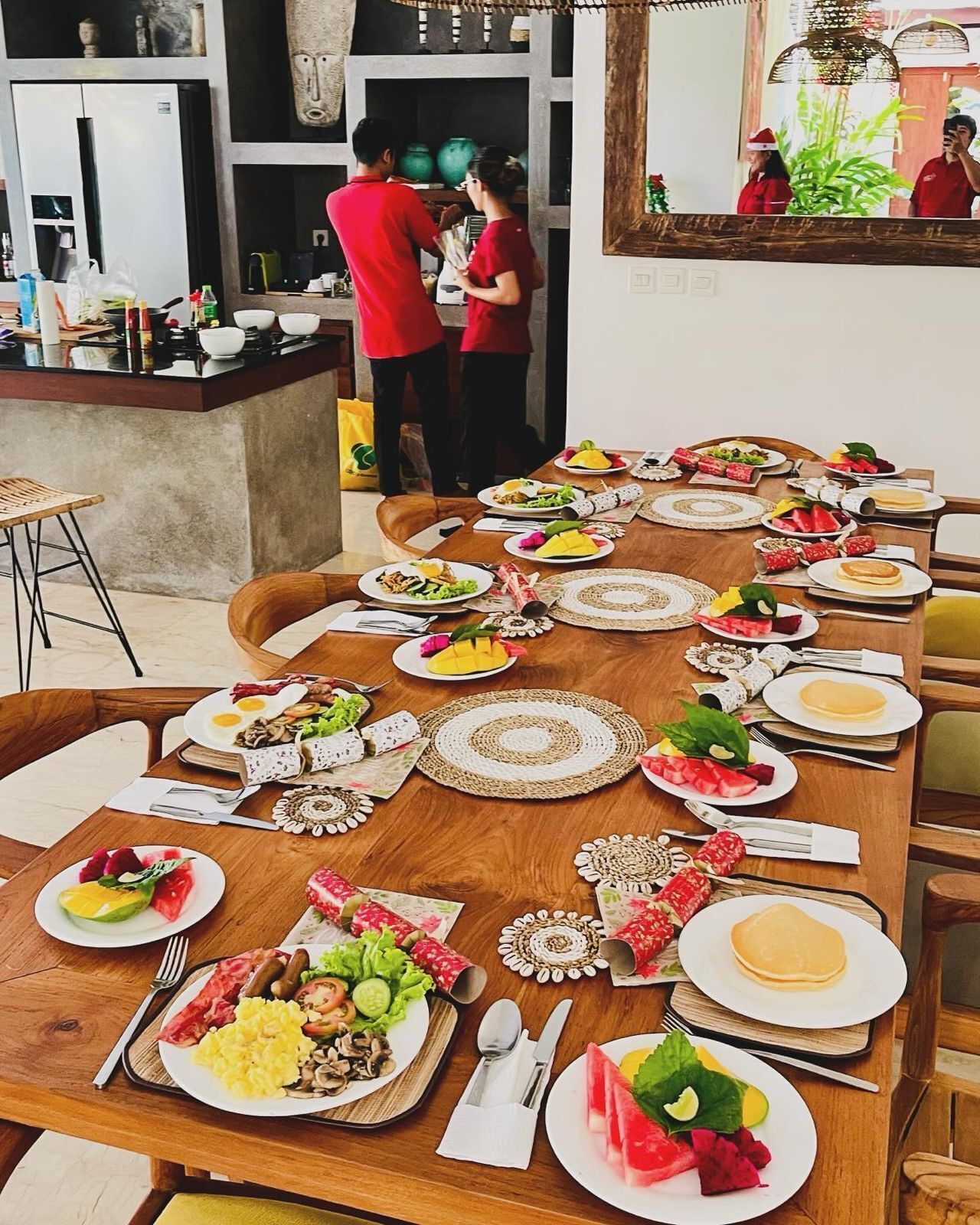 A long dining table set with various dishes and drinks, surrounded by chairs.