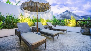 Ein Sitzbereich im Freien mit Korlounge-Stühlen und einem Zier-Sonnenschirm.