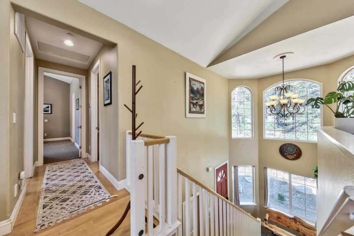 Un escalier orné d’un tapis à motifs, avec une rampe en bois et un lustre.