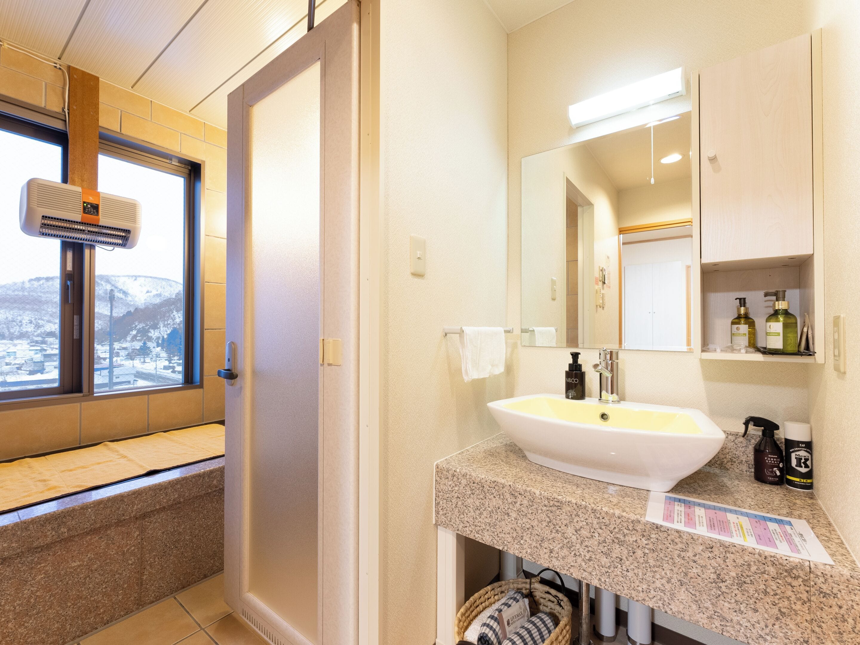 A bathroom with a sink, mirror, and window.