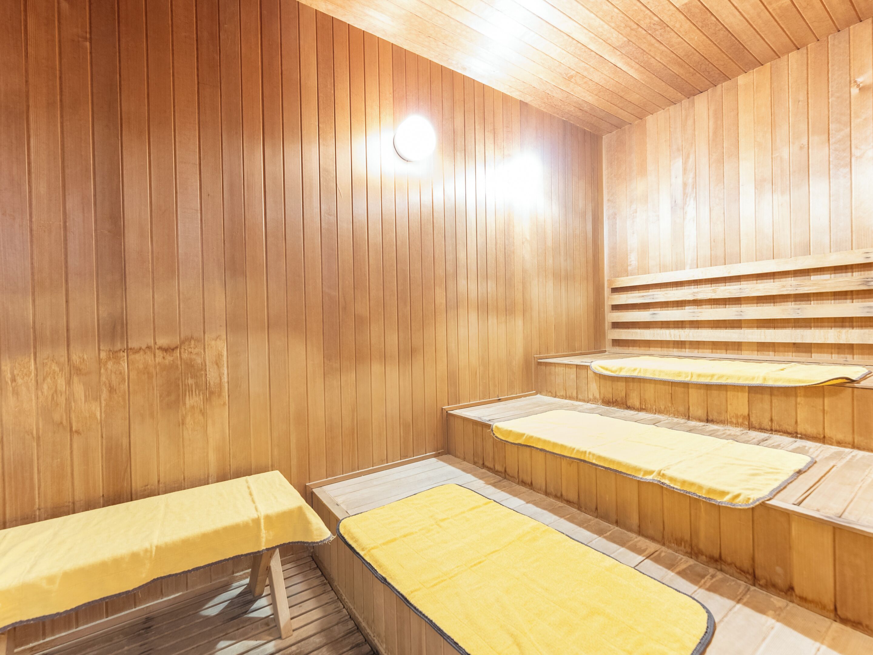 Un sauna avec des murs et des bancs en bois.
