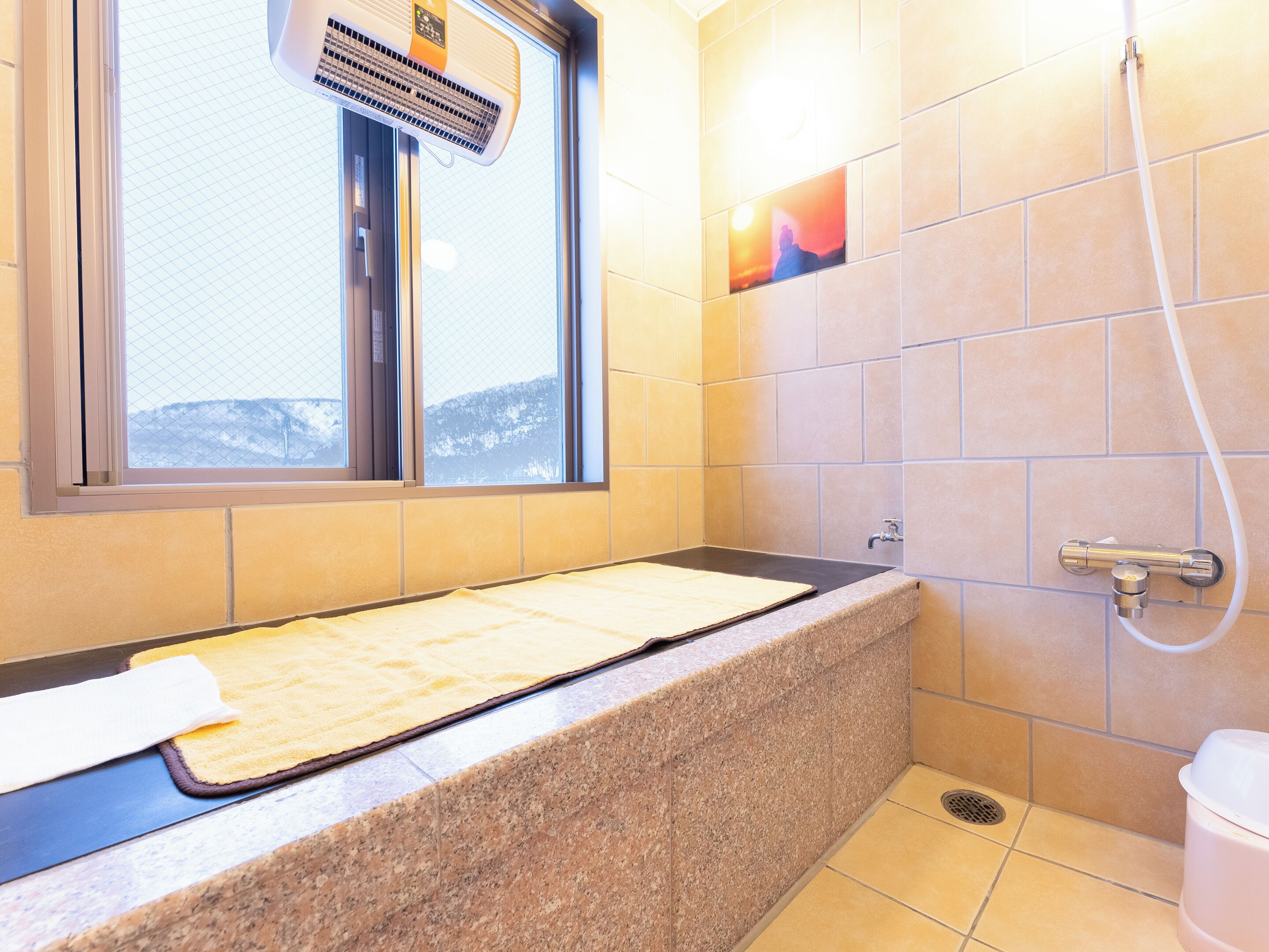 A bathroom with a bathtub, a window, and a shower.