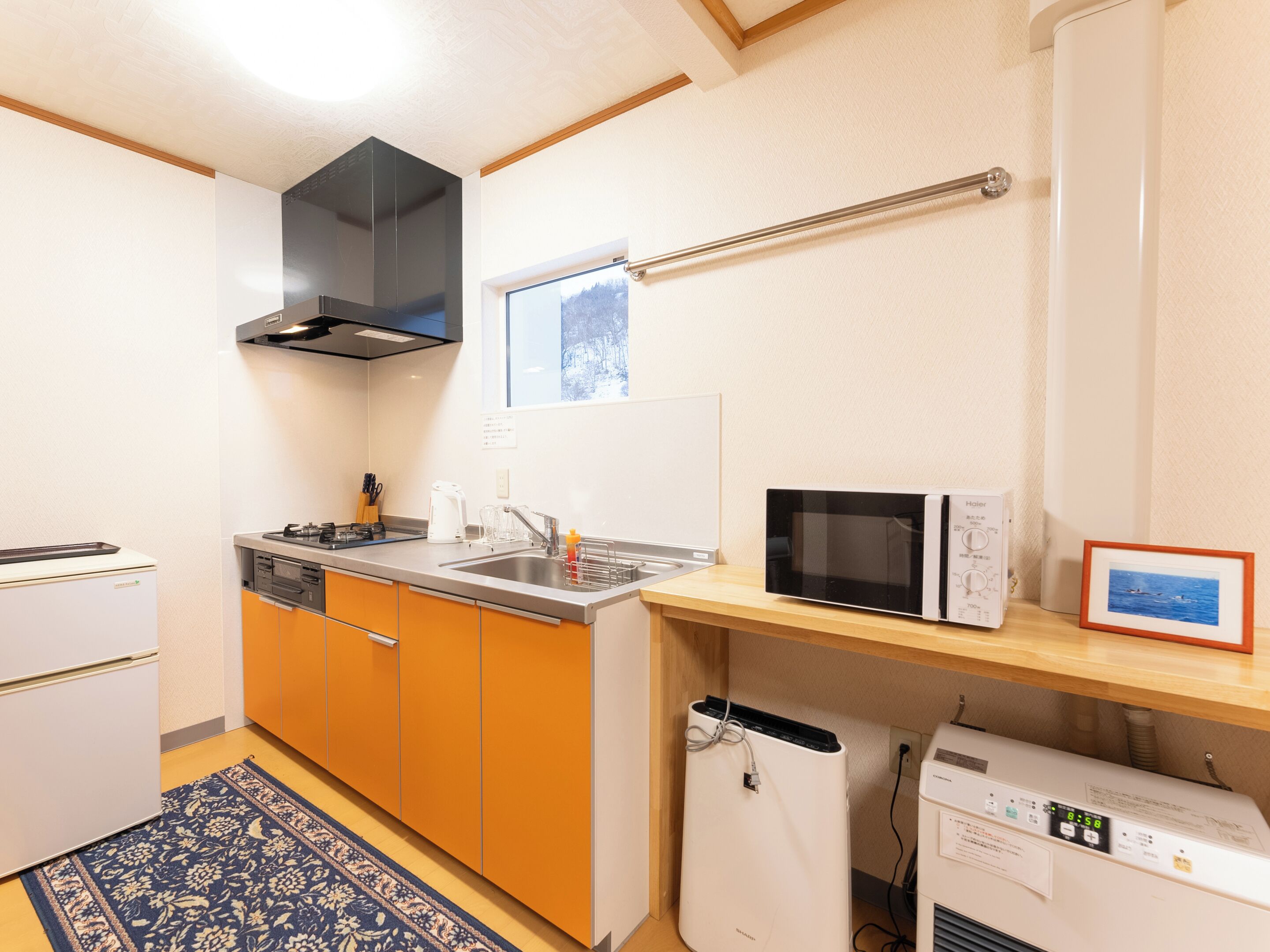Een kleine keuken met een magnetron, broodrooster en spoelbak.