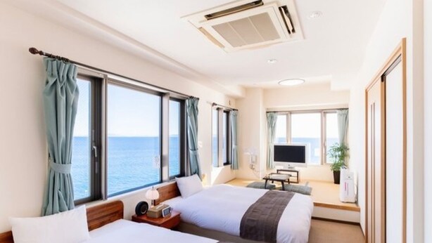 A hotel room with two beds, a TV, and a view of the sea. - Livemax Resort Shiretoko Seafront (Rausu)