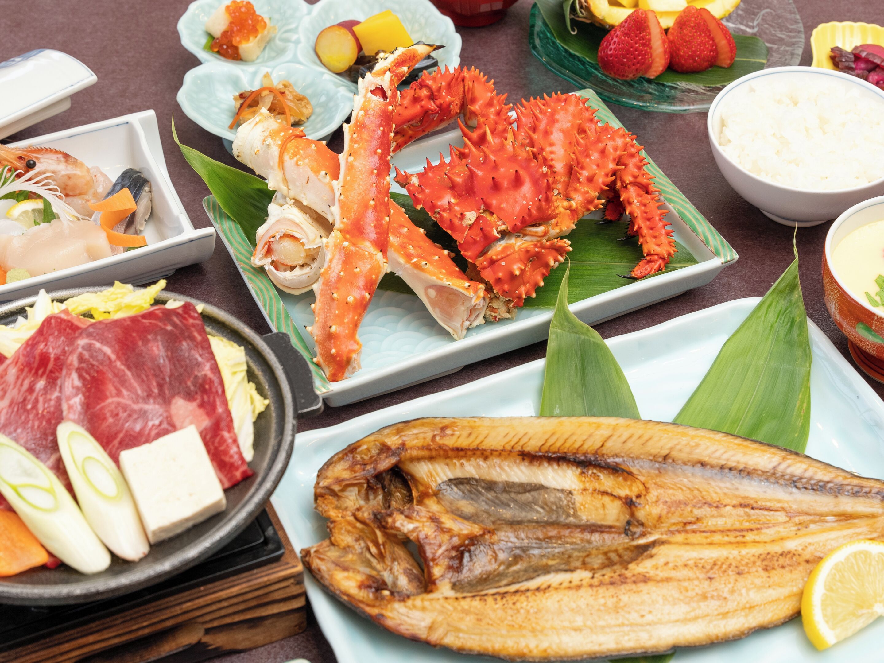 Variedad de platos de mariscos, incluyendo cangrejo, pescado y otros frutos del mar, presentados en una mesa con platos y recipientes.