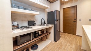 A compact kitchen with a built-in oven, a microwave, a sink, and a refrigerator. - The Teodoro (Tulum)