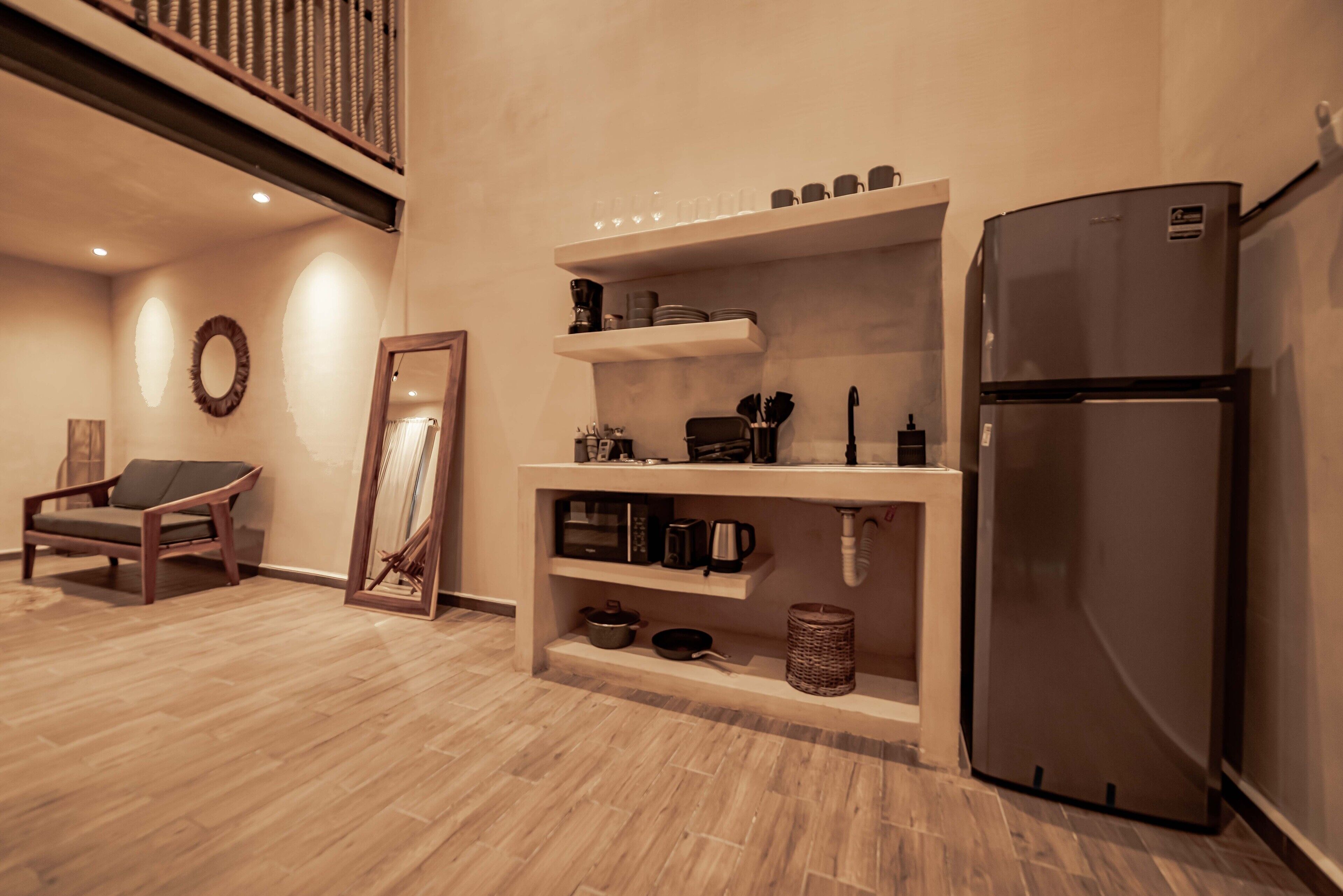 A modern kitchen with a built-in refrigerator, wooden flooring, and a dining area with a chair.