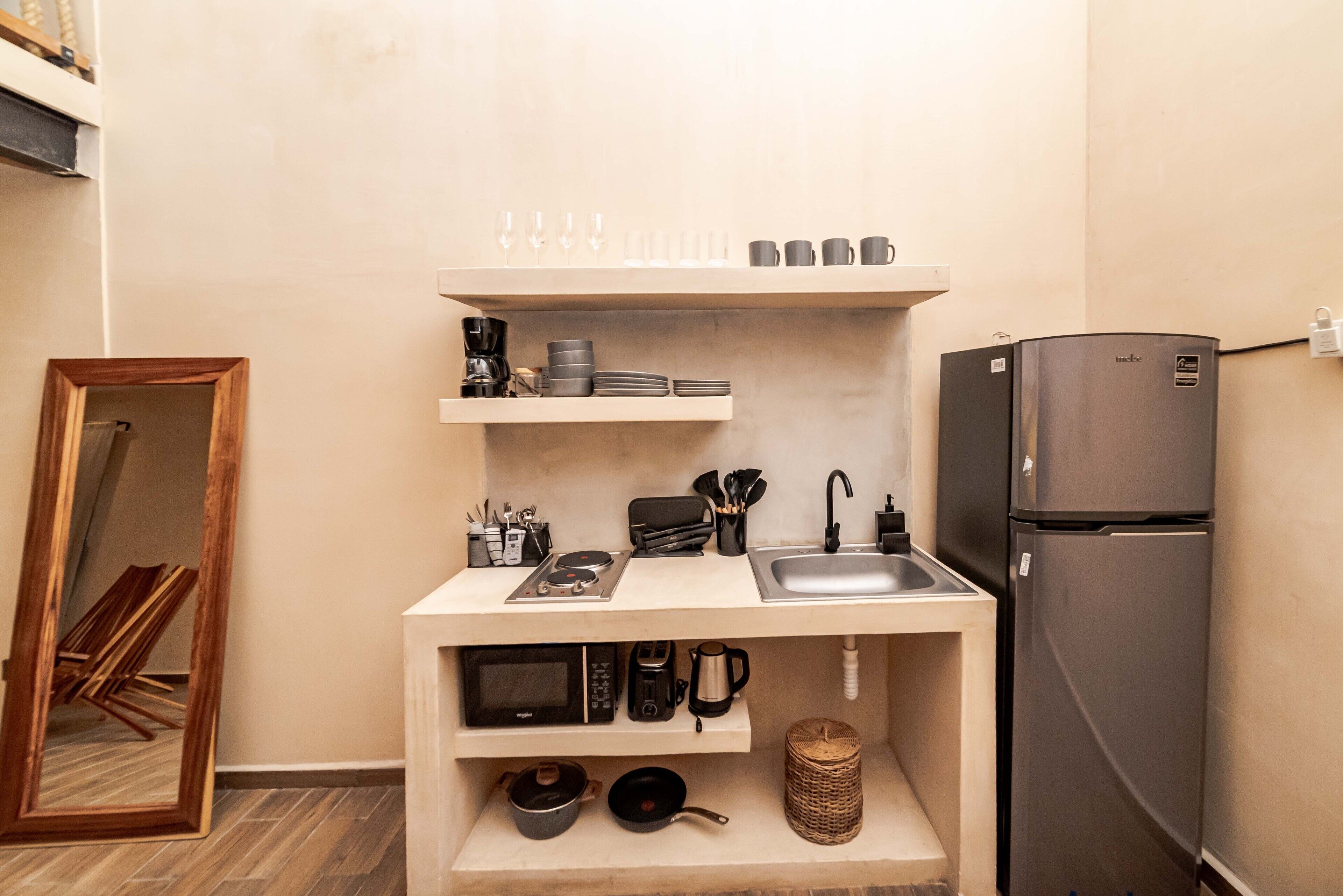 A compact kitchen with a built-in microwave, coffee maker, and a stainless steel refrigerator.