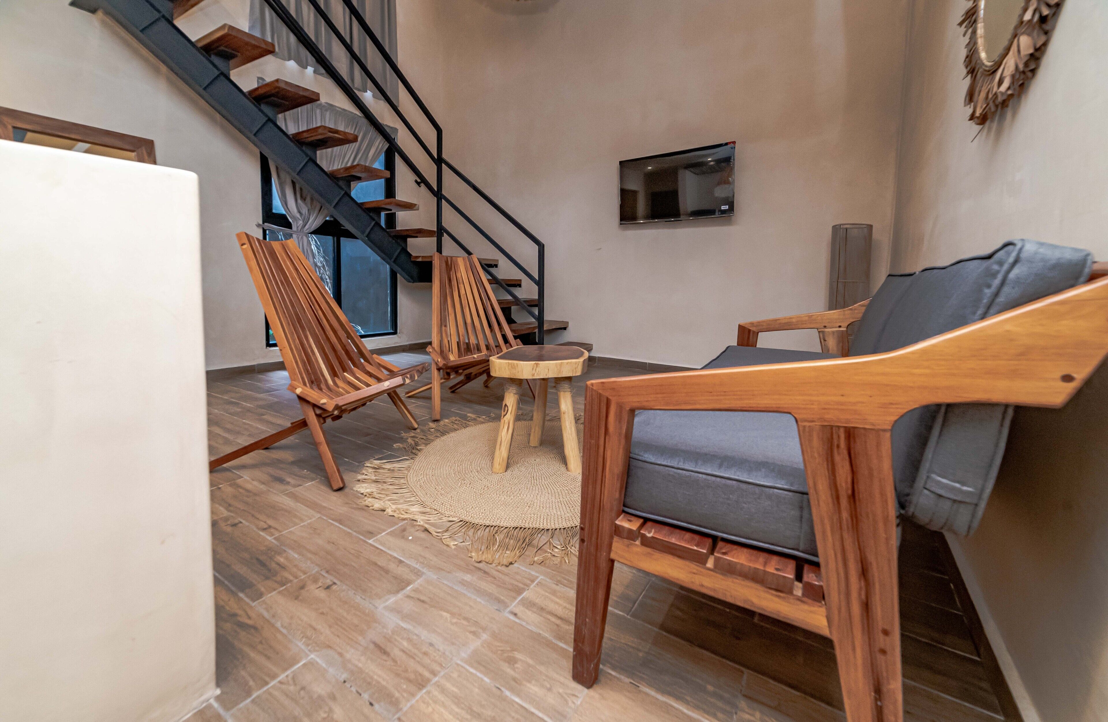 Een moderne woonkamer met houten meubels, een trap en een flatscreen televisie.