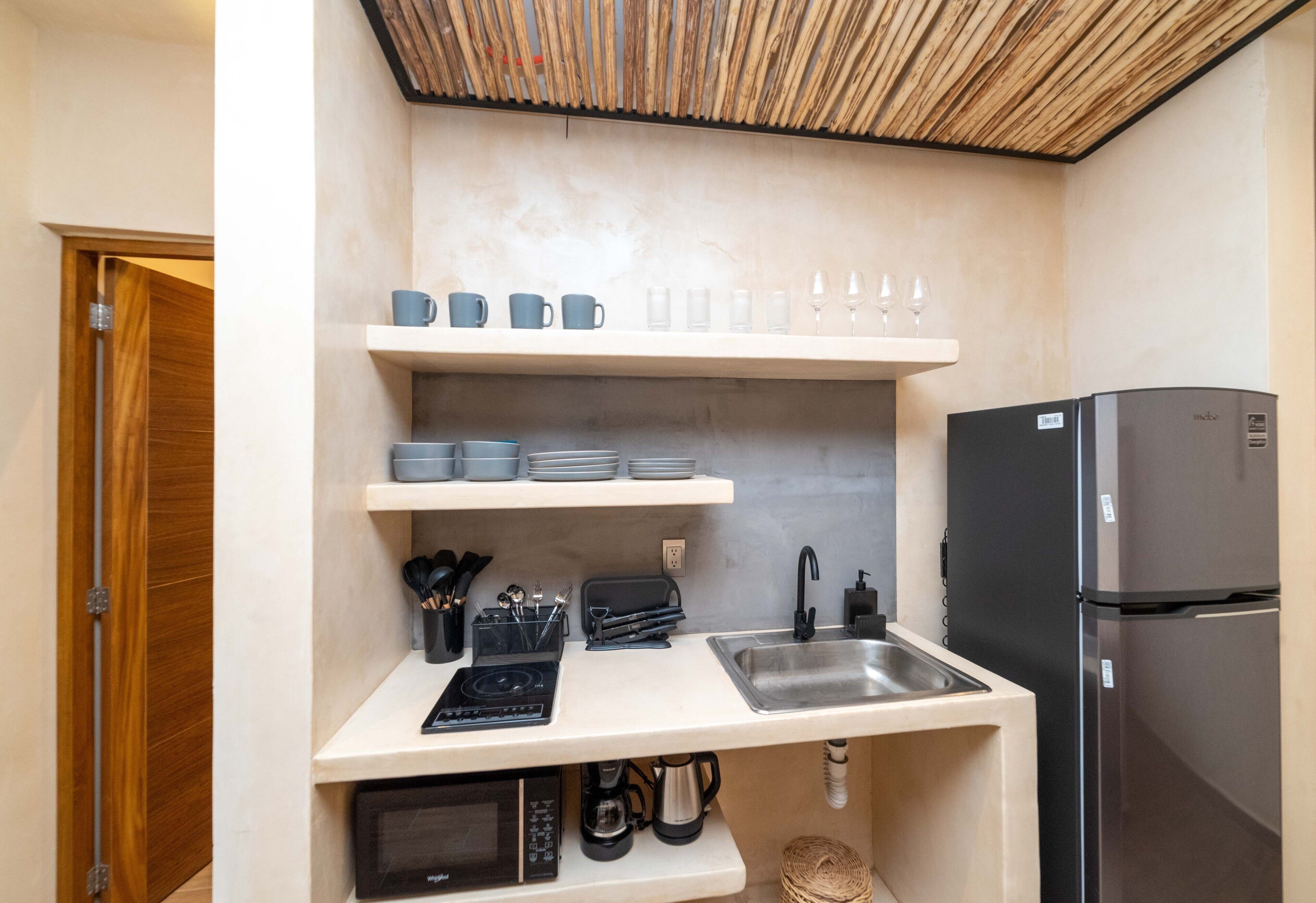 A compact kitchen with a built-in microwave, a coffee maker, and a stainless steel sink.