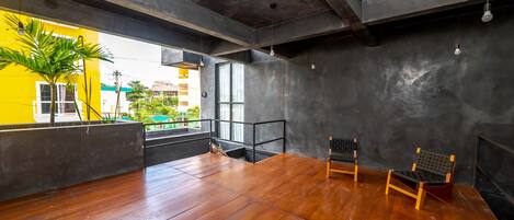Una habitación amplia con suelo de madera, un ventanal grande y vistas a un edificio amarillo.