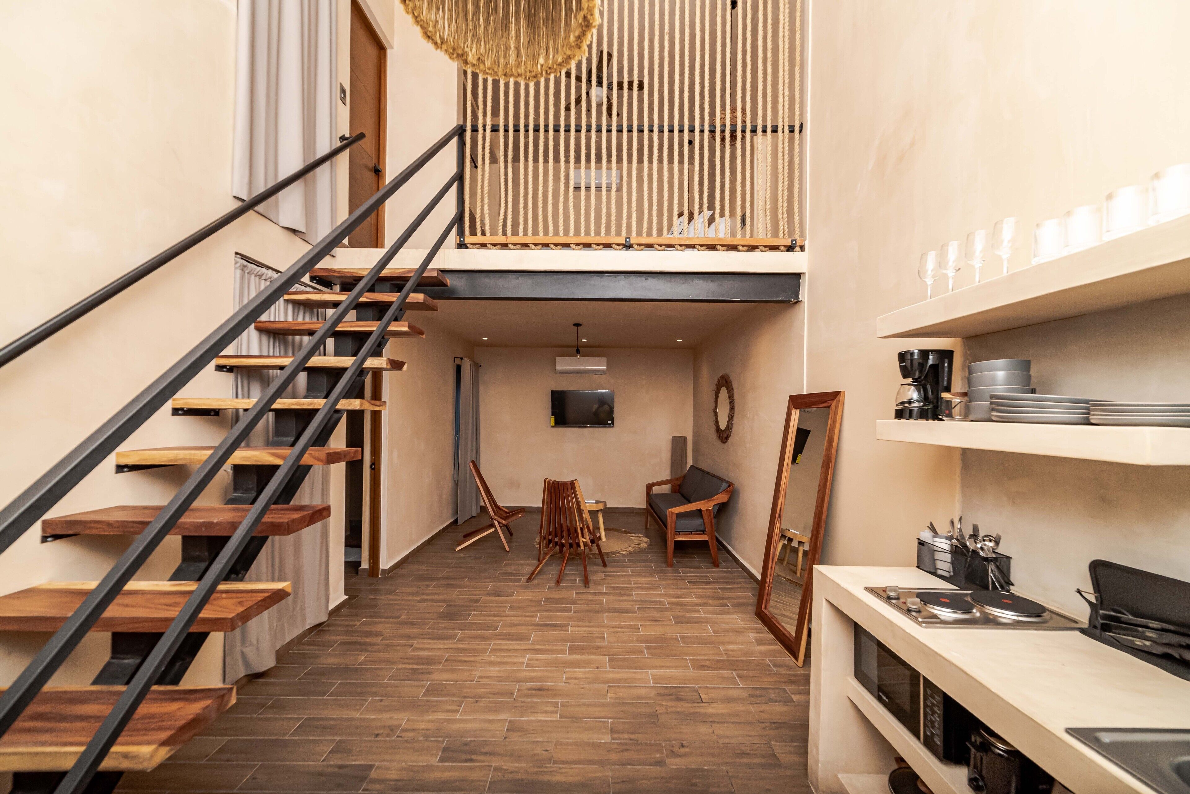 A modern interior with a wooden staircase, a dining area, and a kitchen area.