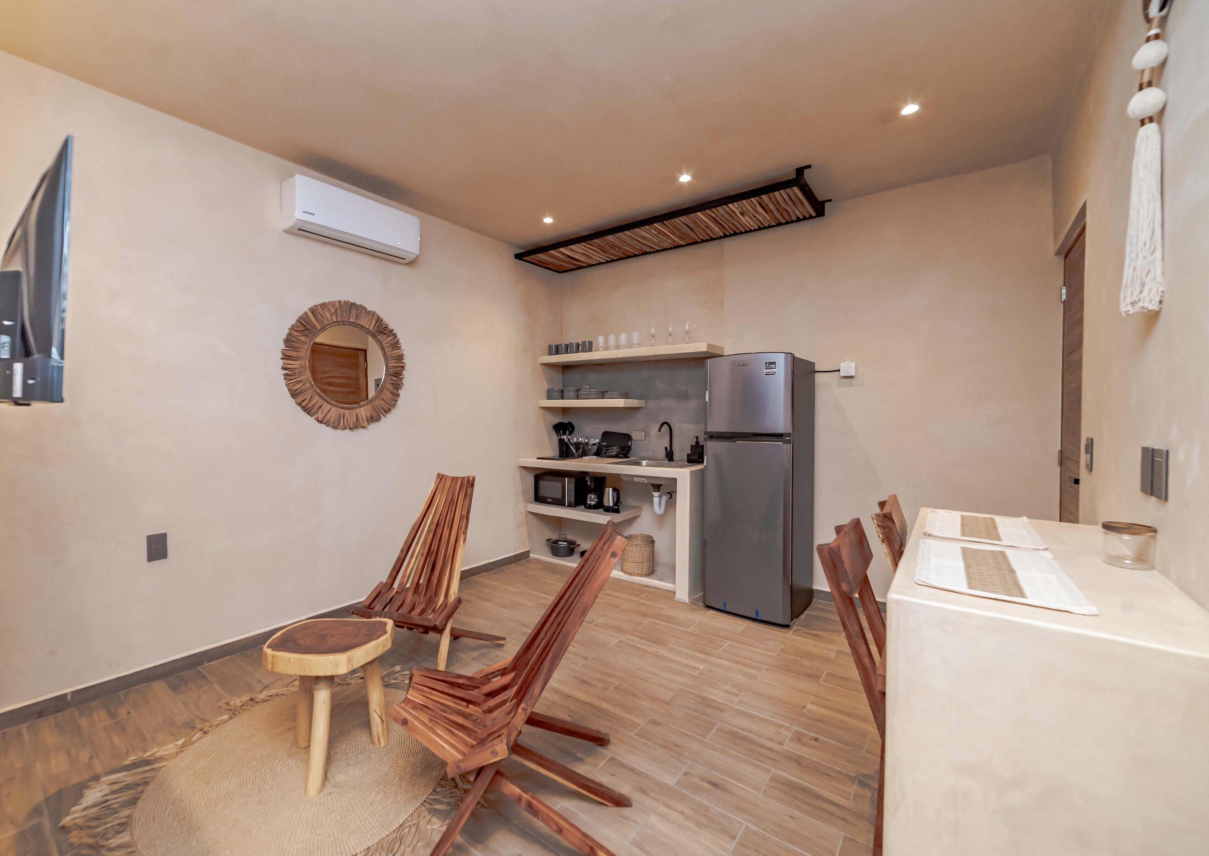 Une cuisine compacte dotée d’un réfrigérateur encastré, de chaises en bois, d’une table à manger et d’un petit îlot central avec un évier.