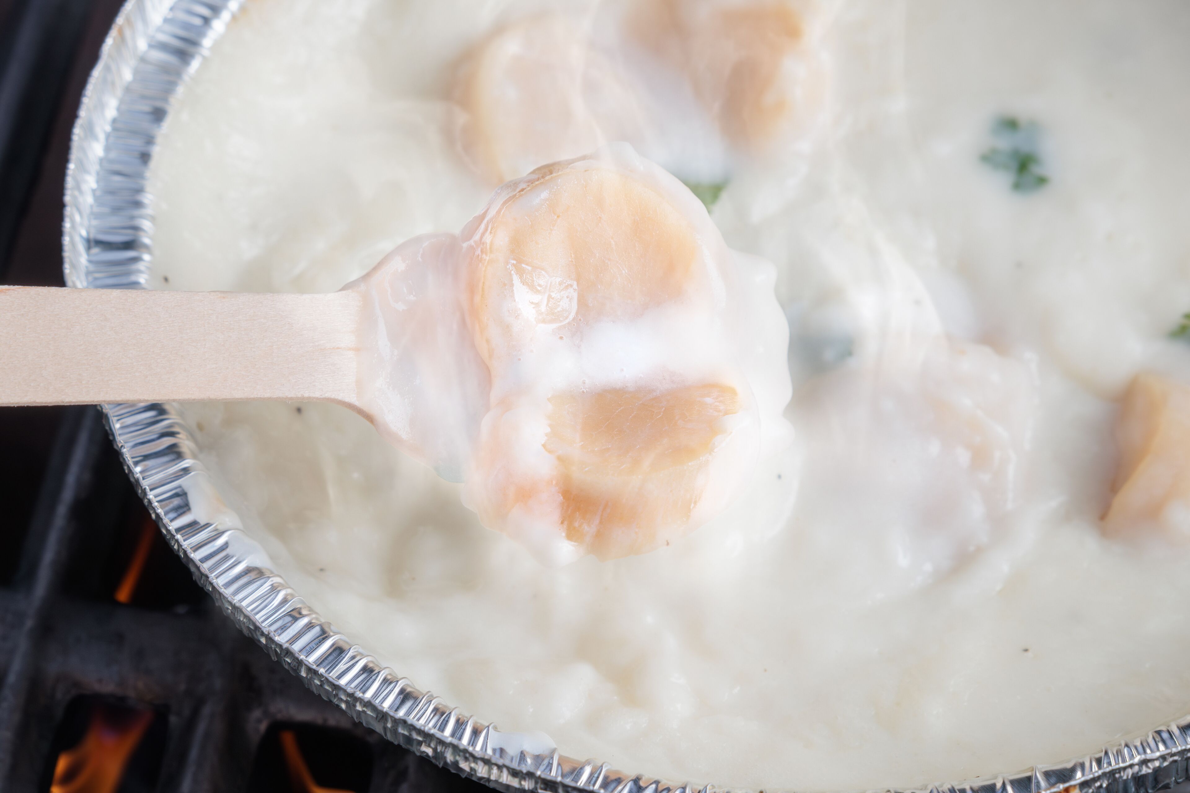 A close-up of a creamy soup with a spoon lifting a piece of food.