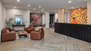 A modern lobby with a reception desk, seating area, and a herringbone-patterned floor.