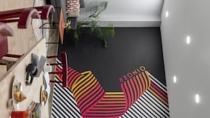 A modern dining area with a black and white striped wall, a wooden table, and red chairs.