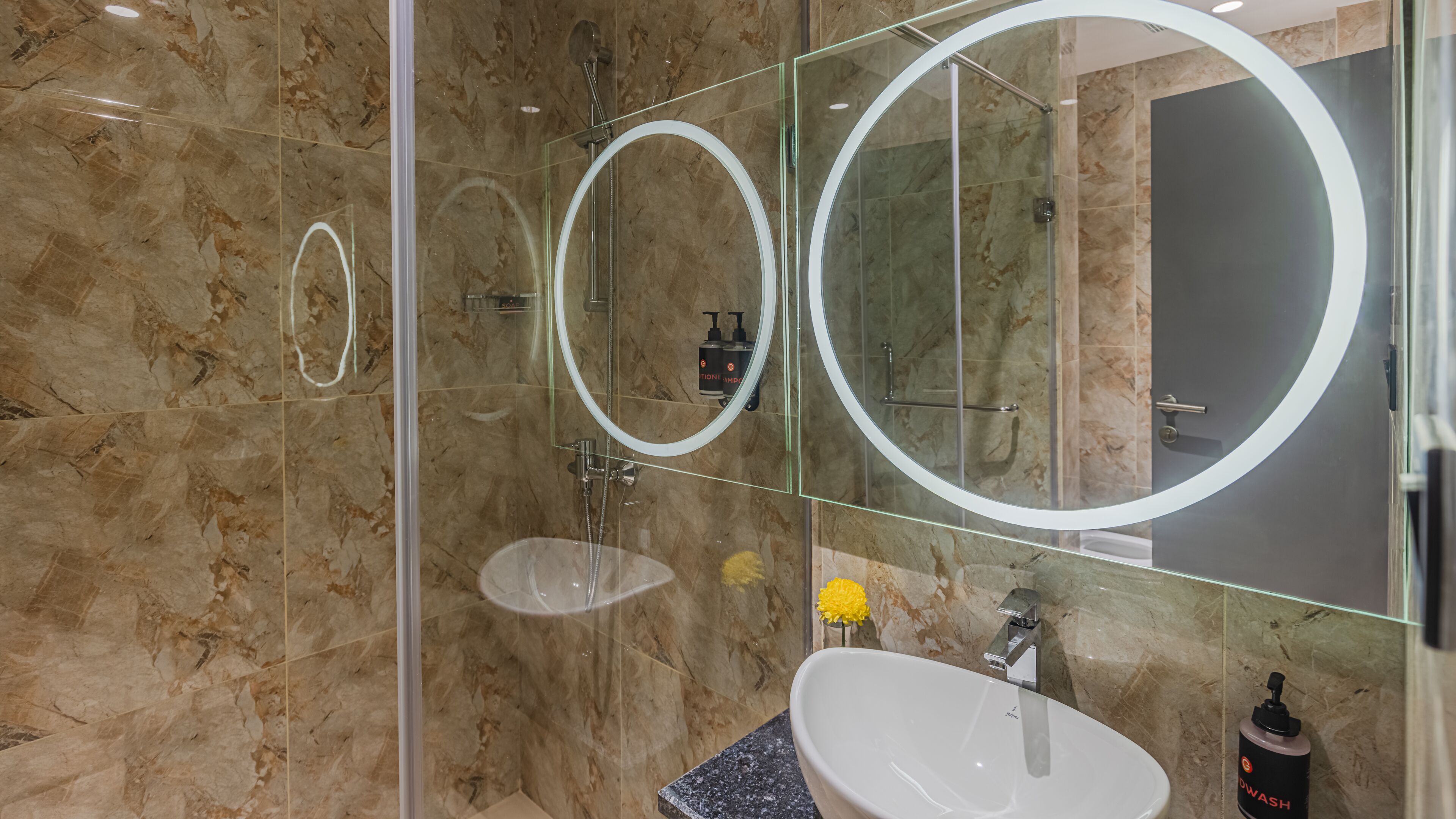 A modern bathroom with a glass-enclosed shower, a white sink, and a large mirror.