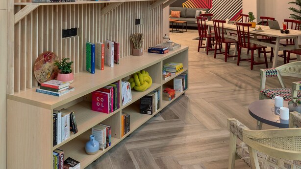 A modern interior with a wooden bookshelf, a dining area, and hanging wicker lamps.