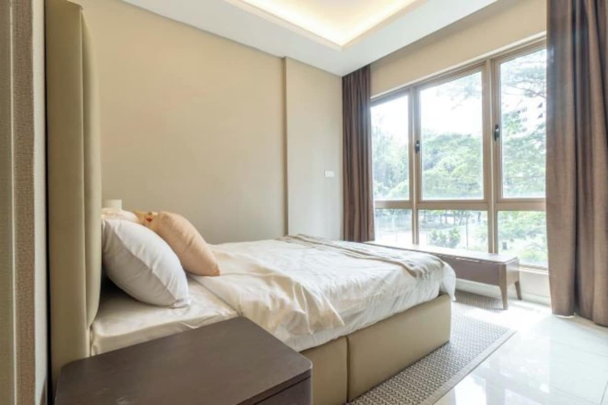 A modern bedroom with a large window, a bed, and a bedside table.