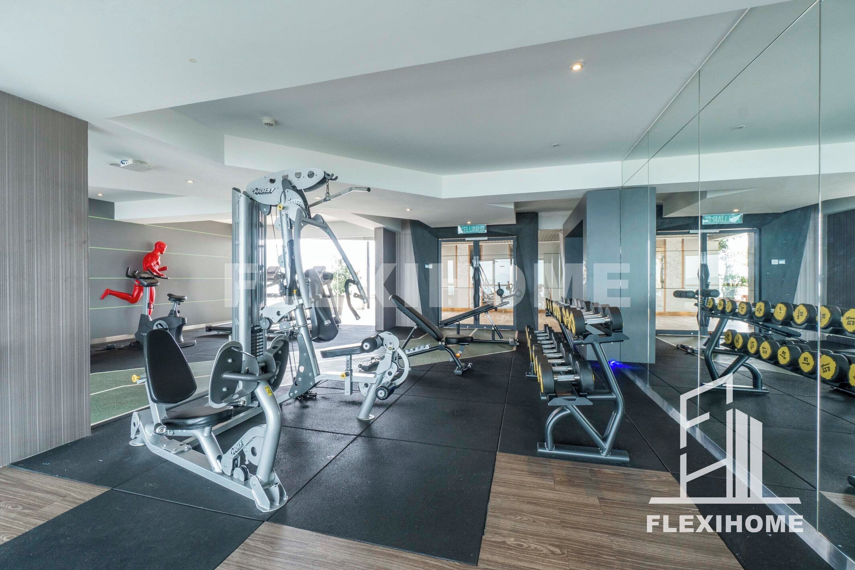 Een moderne sportschool met diverse fitnessapparaten, een rode hometrainer en een spiegelwand.