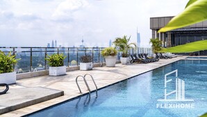 A rooftop pool with a city skyline view, lounge chairs, and potted plants. - Dorsett Residences, Sri Hartamas-KL, Hotel Theme Studio Homes by Flexihome-MY (Kuala Lumpur)