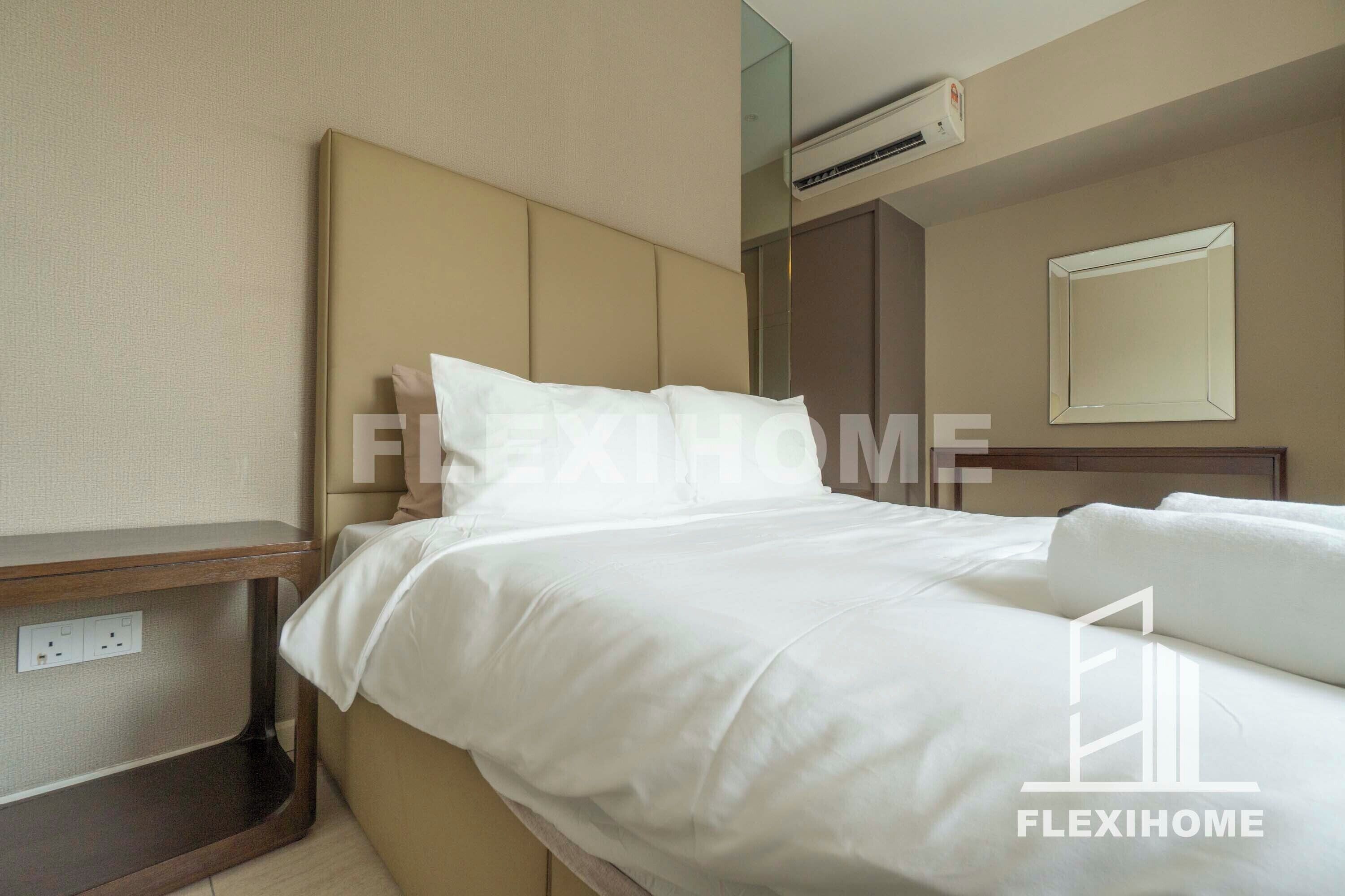 A hotel room with a bed, a bedside table, an air conditioning unit, and a mirror on the wall.