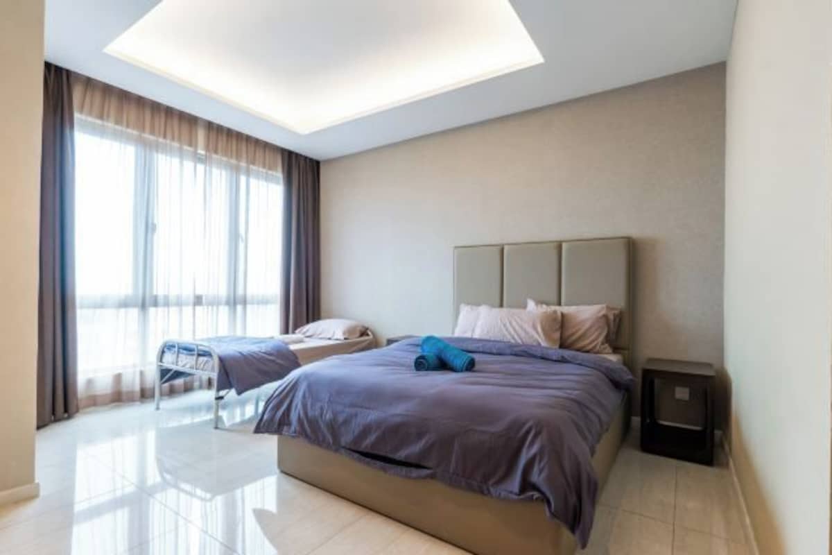 A modern hotel room with a large bed, a smaller bed, a bedside table, and a ceiling light.